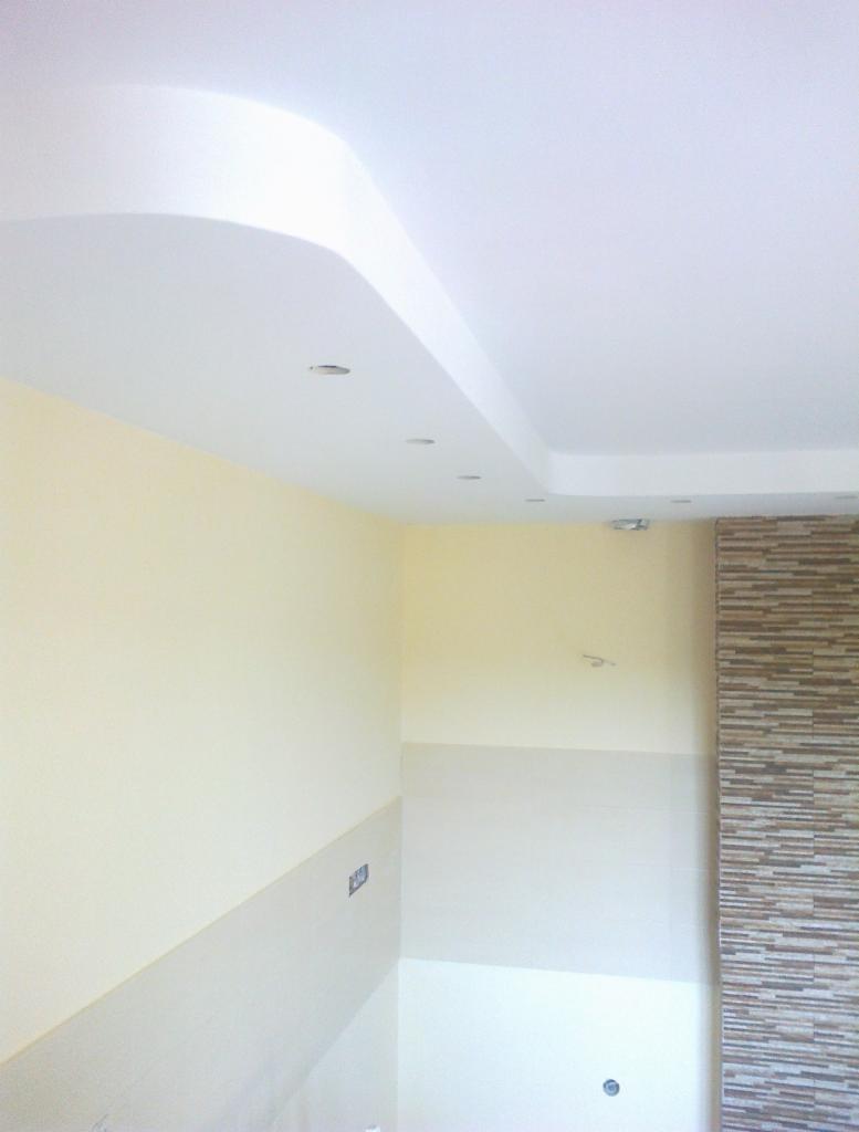 Wykończone wnętrze z podwieszanym sufitem z oświetleniem punktowym i dekoracyjną ścianą z płytek imitujących kamień. Ściany pomalowane na jasny kolor.