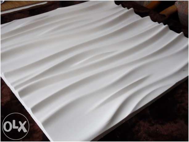 Panel ścienny 3D z falistym wzorem, oświetlony z góry, leżący na ciemnym podłożu. Unikalna faktura i gra światłocieni.