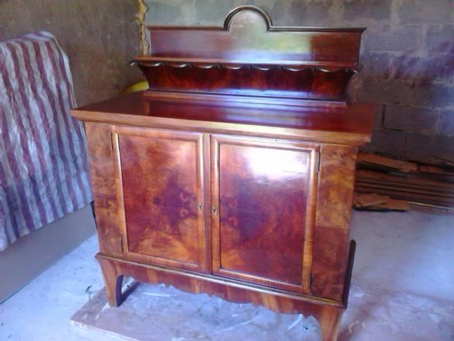 Odrestaurowana, fornirowana komoda w stylu vintage z dwoma drzwiczkami, po renowacji, ukazująca bogate usłojenie drewna i błyszczącą powierzchnię.