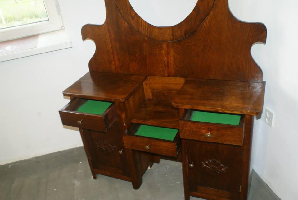 Stylowa, drewniana toaletka z lustrem i otwartymi szufladami wyłożonymi zielonym materiałem, ukazująca rzemiosło stolarskie i dbałość o detale.