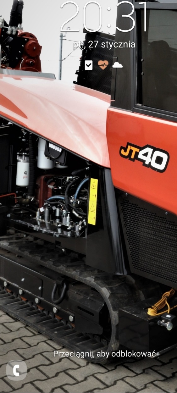 Pomarańczowa wiertnica kierunkowa Ditch Witch JT40 na gąsienicach, widok z boku na silnik i oznaczenia modelu.