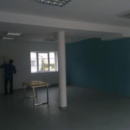 Bart- Bud - Świeżo pomalowane biuro we Wrocławiu z turkusową ścianą i postacią z bajki. Pracownik przy szafkach. Duże okno i kolumna na środku pomieszczenia.