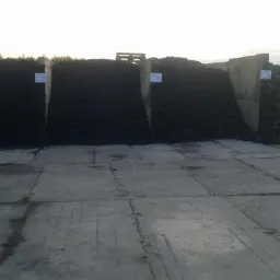 Składowisko węgla w Bielsku Podlaskim z różnymi frakcjami, widoczne betonowe boksy i tabliczki informacyjne.