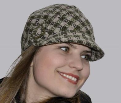 Uśmiechnięta młoda kobieta w tweedowej czapce z daszkiem w odcieniach zieleni i beżu, patrzy w bok.