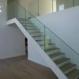 Nowoczesne schody z drewnianymi stopniami i szklaną balustradą w minimalistycznym wnętrzu. Realizacja w Żywcu. Jasne, naturalne światło.