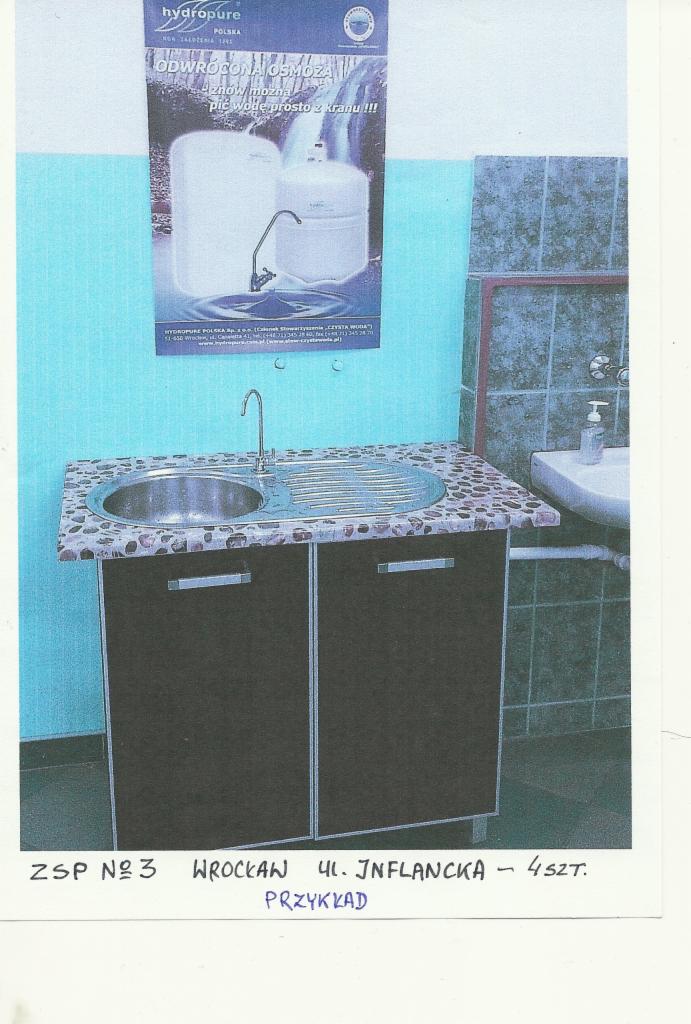 Zlewozmywak z kranem i szafką, nad nim plakat reklamowy z filtrem wody osmotycznej. Widoczne elementy instalacji wodnej. Ujęcie w pomieszczeniu z niebieskimi ścianami.