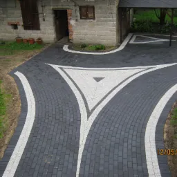 Czarno-biała kostka brukowa ułożona w geometryczny wzór na podjeździe domu. Widok z góry. Wzór w kształcie trójkąta.