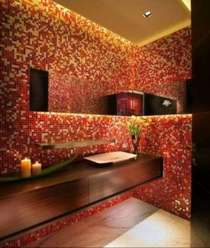 Elegancka łazienka z mozaiką w odcieniach czerwieni i brązu, oświetlona subtelnym światłem, z drewnianą szafką pod umywalką, świecami i dekoracyjnym wazonem z kwiatami.