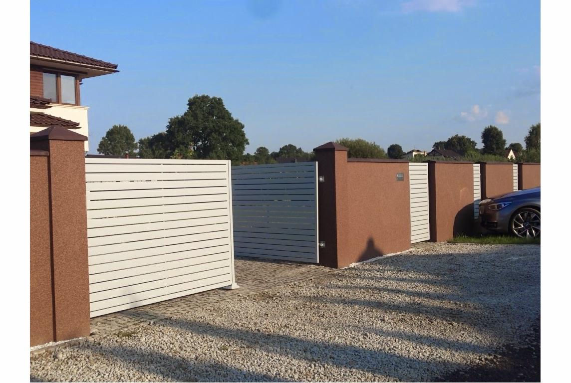 Nowoczesna brama wjazdowa z poziomymi panelami, brązowe słupki z fakturą, częściowo otwarta, widok na podjazd z jasnego żwiru i fragment domu.