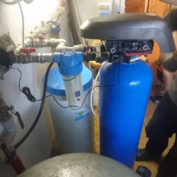 Instalacja filtrów do uzdatniania wody z widocznymi rurami, zaworami i elementami sterującymi, w trakcie montażu przez instalatora.