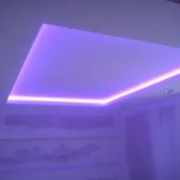 Podwieszany sufit z oświetleniem LED w kolorze fioletowym, widoczny fragment okna i niedokończone ściany. Nowoczesny design wnętrza.