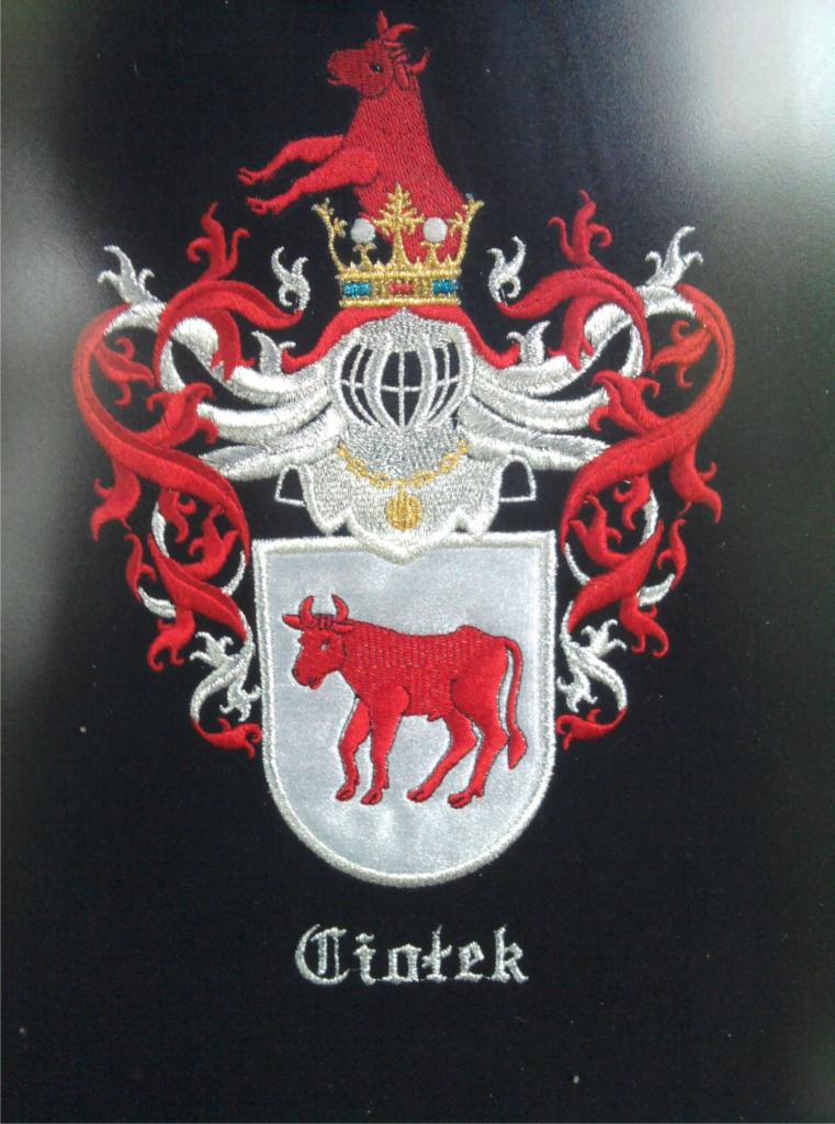 Wyszywany herb rodowy z czerwonym koniem i bykiem na czarnym tle.