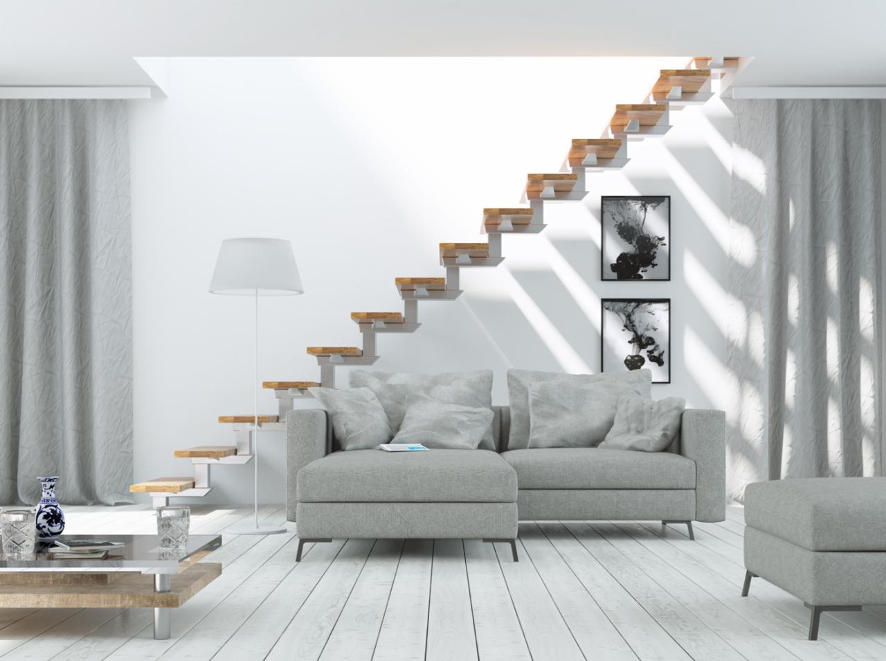 Minimalistyczne wnętrze z drewnianymi schodami wspornikowymi, szarą sofą i białymi ścianami, oświetlone naturalnym światłem wpadającym przez okno dachowe.