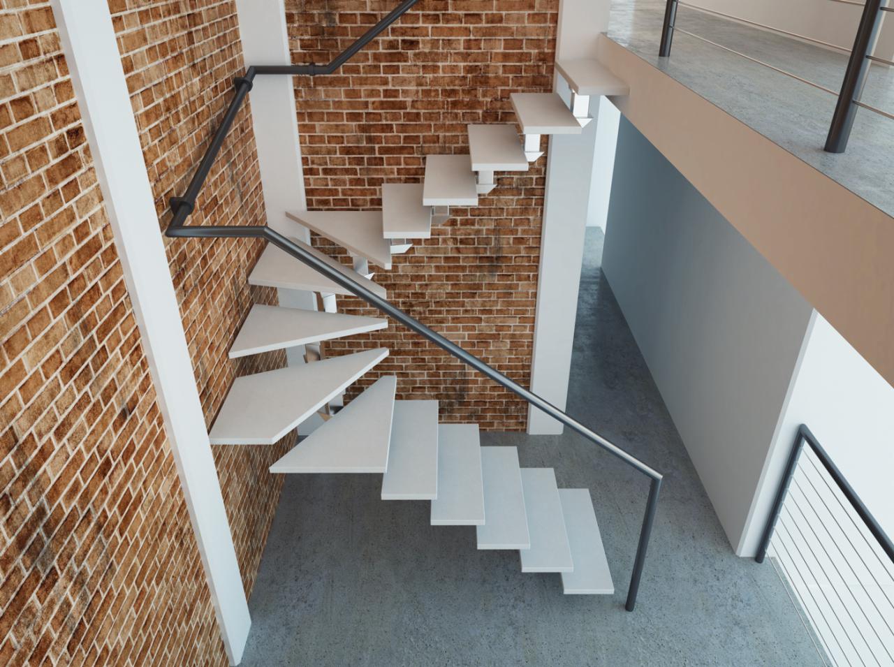Nowoczesne schody wspornikowe z białymi stopniami i metalową balustradą na tle ceglanej ściany, widziane z góry. Minimalistyczny design i industrialne akcenty.