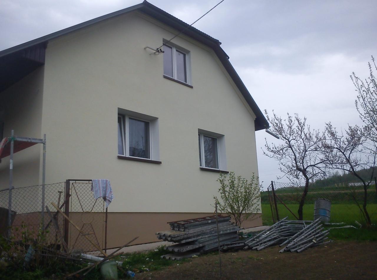 Dom z jasną elewacją po renowacji, widoczne rusztowania i narzędzia, co sugeruje prace wykończeniowe. Uwagę zwraca świeżo pomalowana fasada i schludny wygląd budynku.