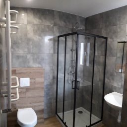 MK Firma Usługowa Michał Kohnke - Nowoczesna łazienka z kabiną prysznicową z czarnymi profilami, umywalką nablatową i dużymi szarymi płytkami imitującymi beton.