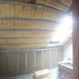 MK Firma Usługowa Michał Kohnke - Poddasze w trakcie ocieplania wełną mineralną, widoczne profile metalowe i okno dachowe, paczki wełny ROCKWOOL w tle.