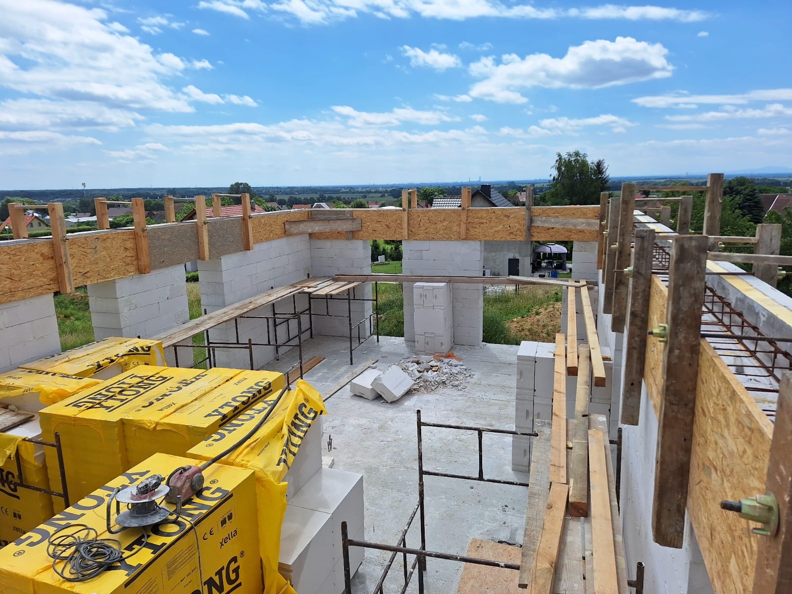 Wznoszenie ścian domu murowanego z bloczków Ytong w Trzebnicy, widok z góry na budowę w trakcie realizacji, z widocznymi materiałami budowlanymi i narzędziami.