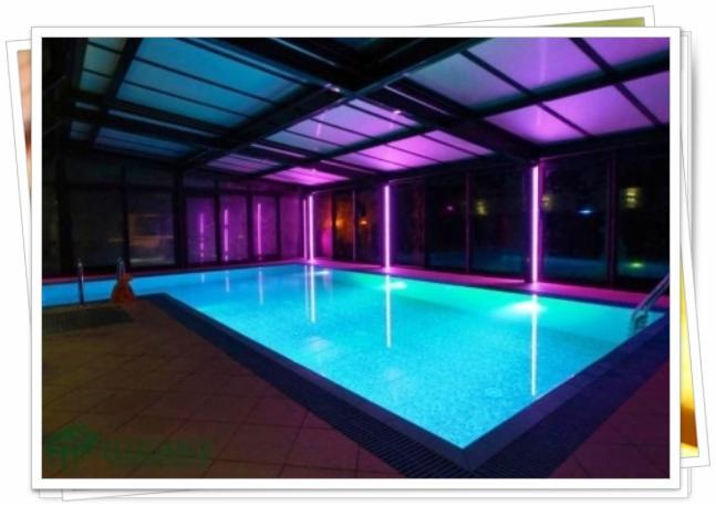 Kryty basen z oświetleniem LED w Łomży, z przeszklonym dachem i ścianami, tworzący nowoczesną przestrzeń relaksu i rekreacji.