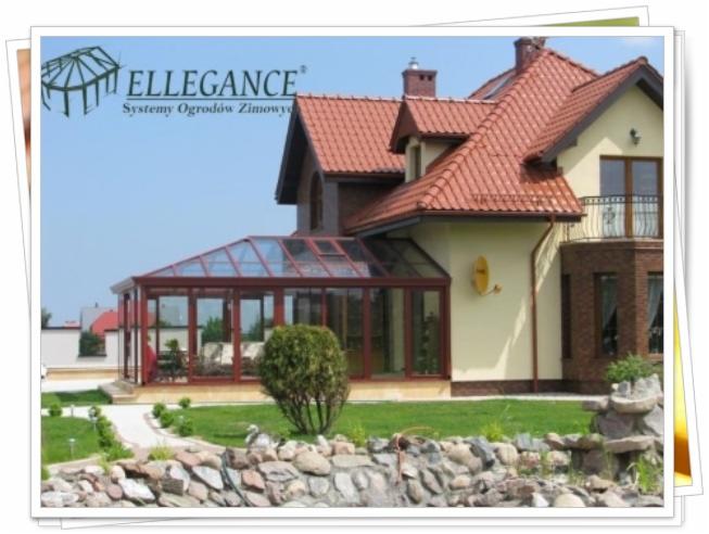 Szklana oranżeria przylegająca do domu z czerwonym dachem, otoczona zielonym trawnikiem i ozdobnym skalniakiem. Widoczny fragment logo 'ELLEGANCE'.
