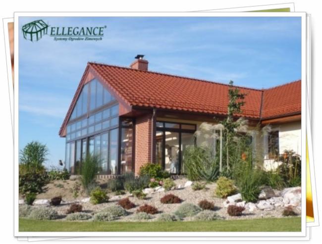 Dom z ogrodem zimowym i zagospodarowanym terenem. Widoczne rośliny ozdobne, kamienie i trawy. Dach z czerwonej dachówki.