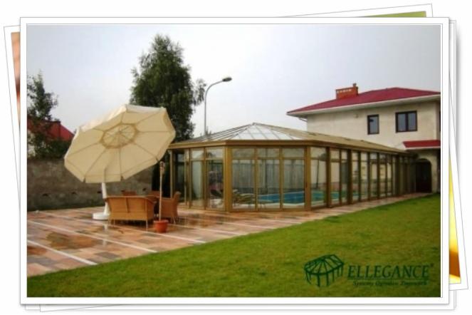 Przeszklona altana przy domu z basenem, widoczny parasol i meble ogrodowe na patio. Trawa w pierwszym planie, dom z czerwonym dachem w tle.