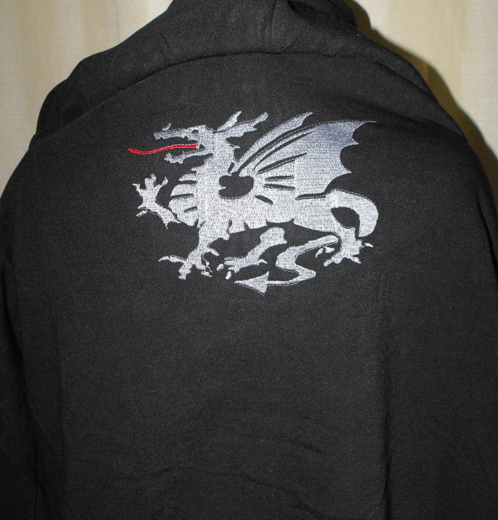 Czarna bluza z kapturem, na plecach haftowany srebrny smok z czerwonym językiem. Widok z tyłu, detale haftu.