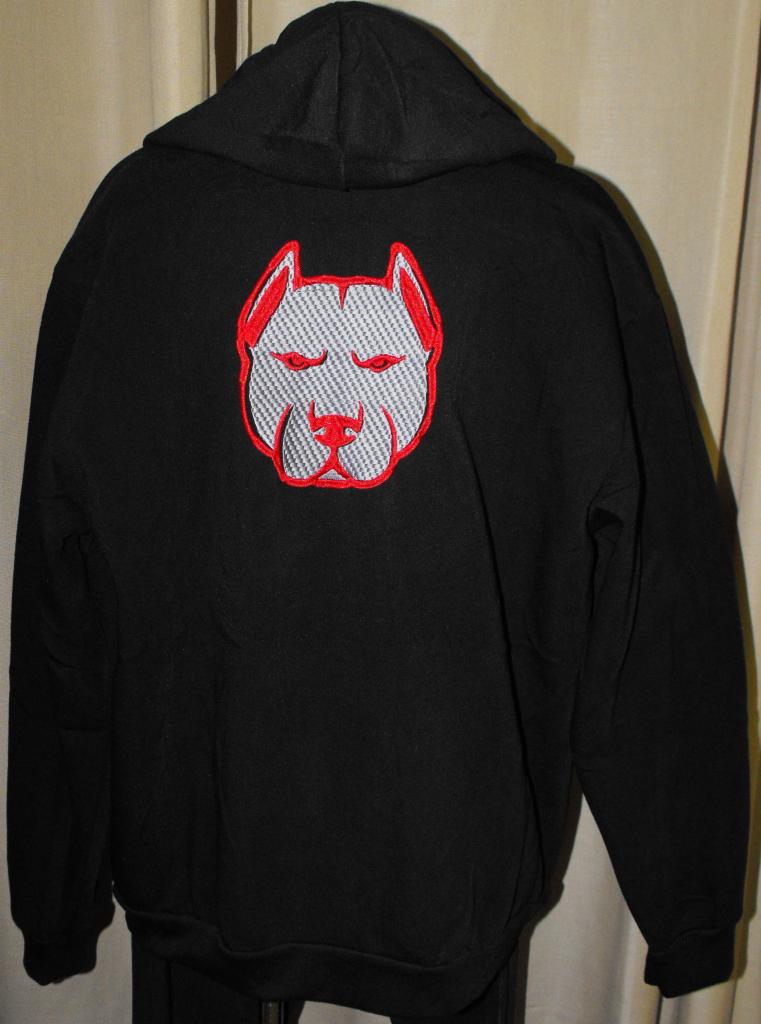 Czarna bluza z kapturem, na plecach wyhaftowany wizerunek głowy psa rasy pitbull w kolorach szaro-czerwonym. Widok z tyłu, neutralne tło.