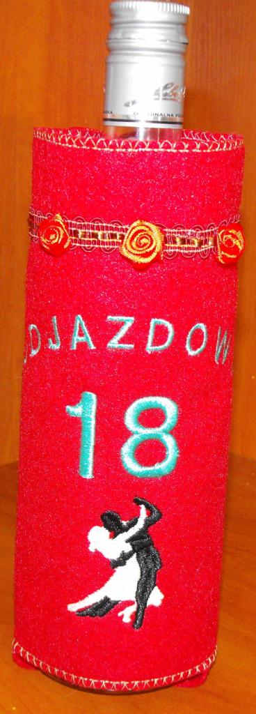 Ozdobna, czerwona osłonka na butelkę z haftowanymi aplikacjami: napisem 'DJAZDOW', liczbą '18' i tańczącą parą. Dekorowana wstążką z różyczkami.