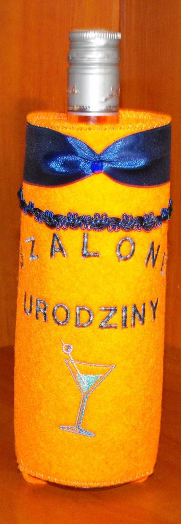 Ozdobna, pomarańczowa osłonka na butelkę z napisem 'Szalone Urodziny', dekorowana niebieską kokardą i haftowanym kieliszkiem koktajlowym.