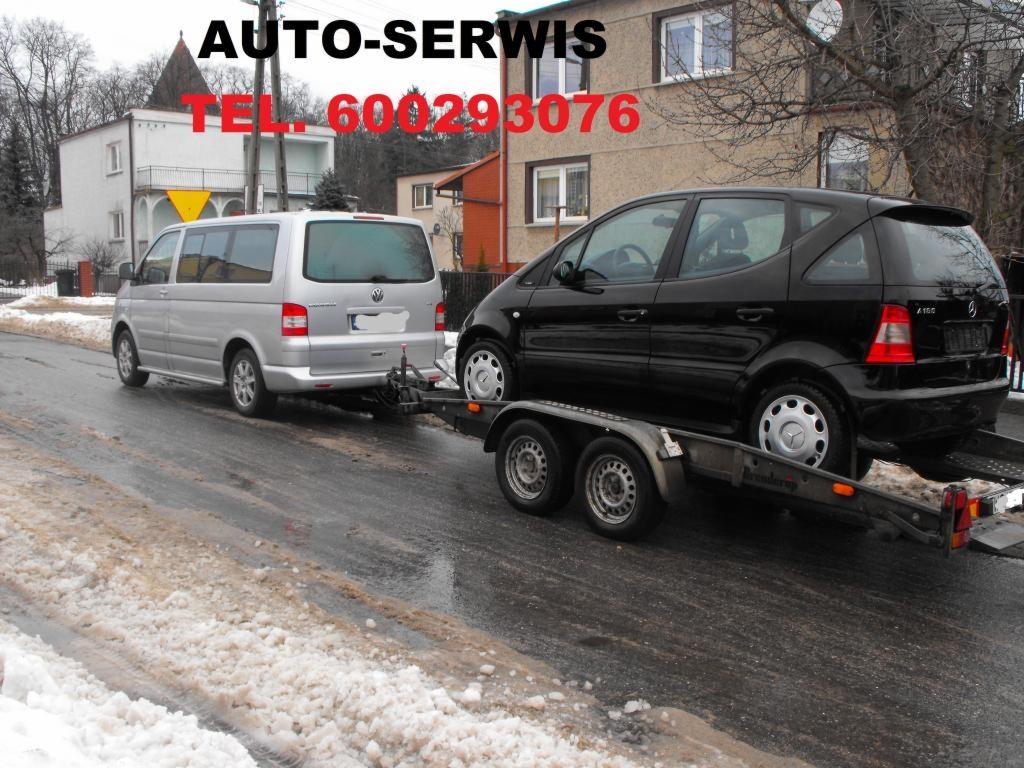 Srebrny van holowniczy z czarnym Mercedesem na przyczepie na zasypanej śniegiem drodze. Auto-Serwis TEL. 600293076 na zdjęciu.
