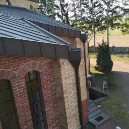 Metalowe rynny i nowy dach na budynku z cegły, widok z góry, drabina oparta o ścianę w tle.