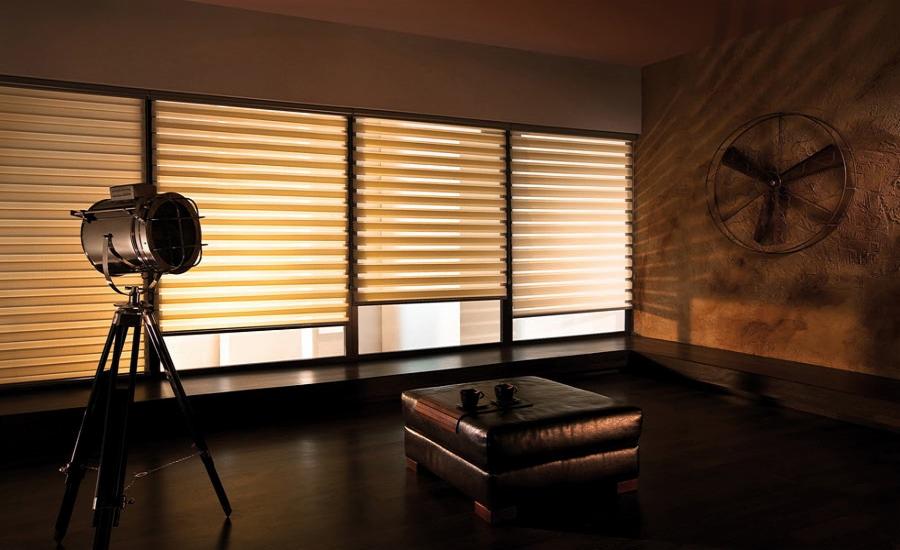 Eleganckie wnętrze z trzema oknami przesłoniętymi roletami poziomymi dzień noc w odcieniach beżu i bieli, oświetlone studyjną lampą na trójnogu, z dekoracyjnym wiatrakiem na ścianie i skórzanym...