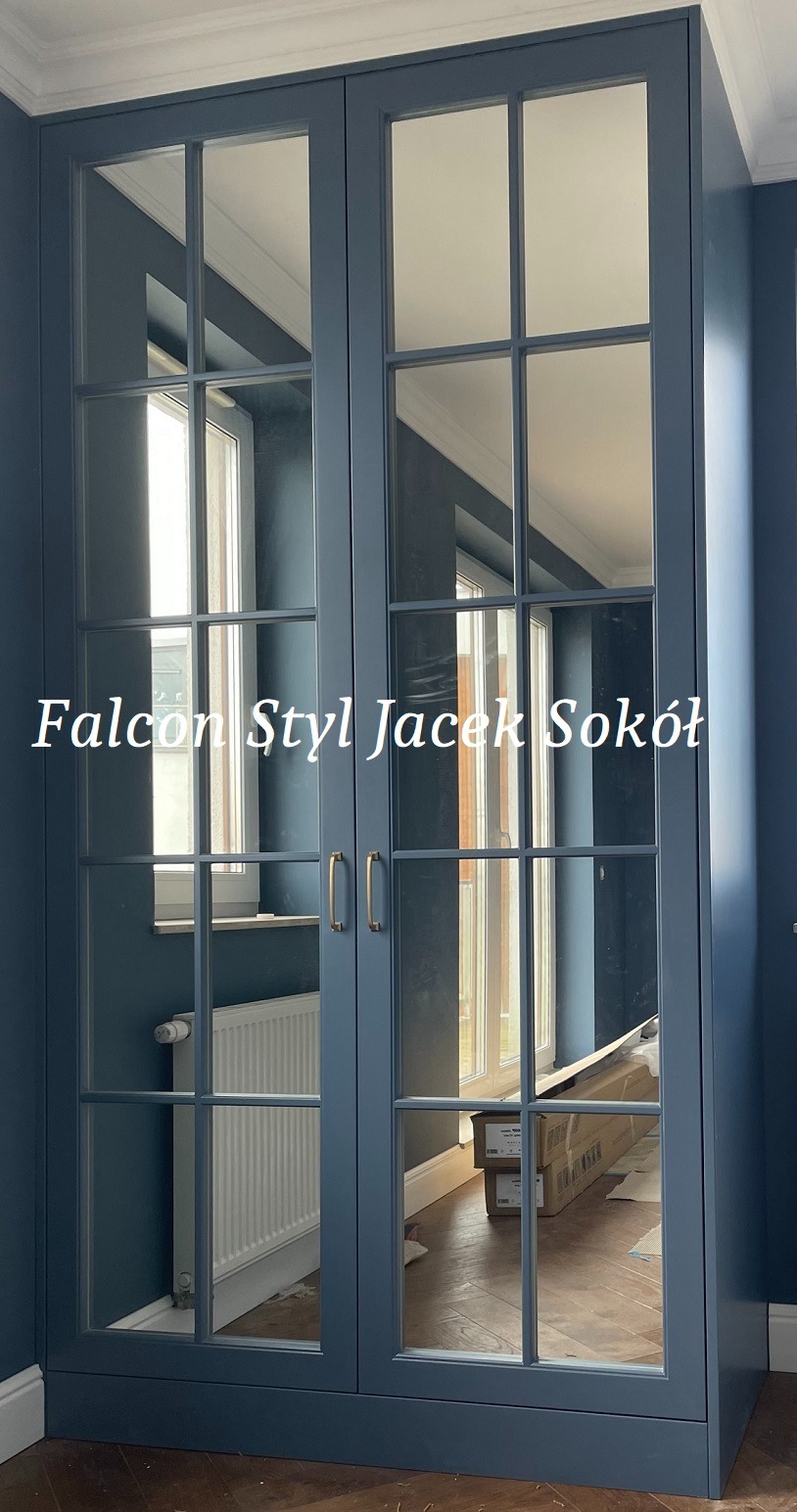 Niebieska szafa z przeszklonymi drzwiami w stylu angielskim, widoczne odbicie wnętrza pokoju z grzejnikiem i kartonami, podłoga z parkietu.