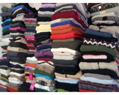 Rząd ułożonych w stosy, kolorowych swetrów z dzianiny, wełny i innych materiałów. Ubrania są złożone i ułożone jeden na drugim, tworząc wysokie stosy.