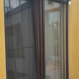 Zewnętrzna moskitiera plisowana zamontowana na oknie tarasowym, widoczne dwie doniczki z lawendą na szarym tarasie.