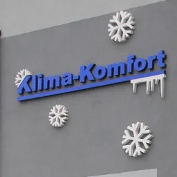 Niebieski napis 'Klima-Komfort' na szarej ścianie, ozdobiony białymi śnieżynkami i imitacją sopli lodu, sugerujący usługi związane z komfortem klimatycznym.