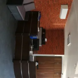 Wnętrze biura z ekspozycją systemów wentylacyjnych i klimatyzacyjnych różnych marek, w tym Midea i Rotenso, na tle ściany z cegły.