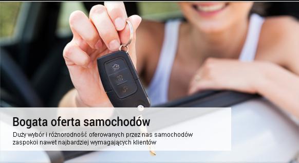 Kobieta uśmiecha się, trzymając kluczyk samochodowy w dłoni, opierając się o biały samochód.