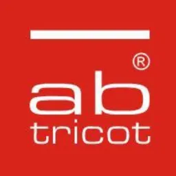 Czerwone logo AB Tricot z białą poziomą linią u góry. Minimalistyczny design z wyraźnym napisem i znakiem zastrzeżonym.