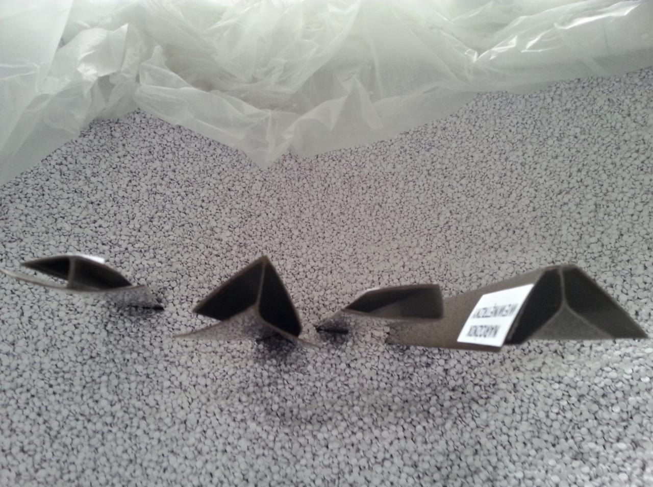 Przekroje rynny z etykietą na tle granulatu styropianu w worku foliowym. Prezentacja kształtu i materiału.