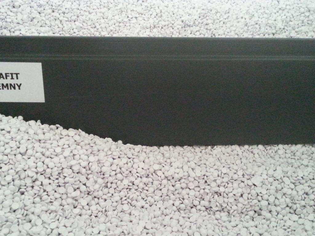 Grafitowy styropian w granulkach, widoczny fragment etykiety. Materiał ociepleniowy w zbliżeniu, szare tworzywo.