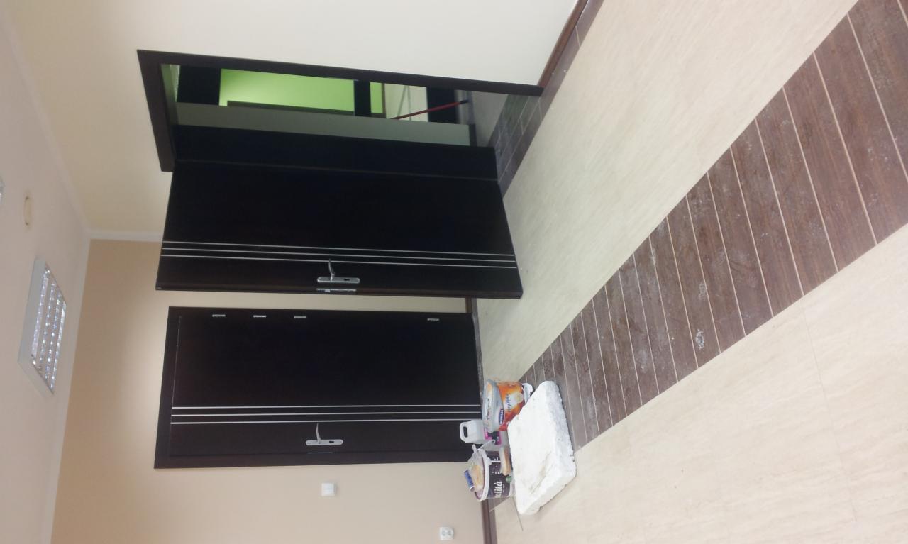 Wykończone wnętrze z ciemnymi szafkami w zabudowie i ozdobnym pasem na podłodze. Widoczne puszki z farbą. Nietypowy kadr z bliska.