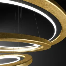 Trzy złote, okrągłe lampy wiszące z wbudowanym białym światłem LED, zawieszone na cienkich linkach na tle ciemnego sufitu.
