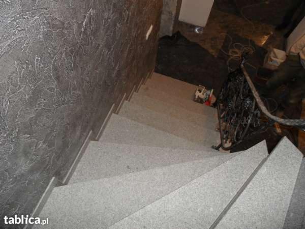 Granitowe schody wewnętrzne z ozdobną ścianą o fakturze betonu architektonicznego, widok z góry, fragment balustrady.