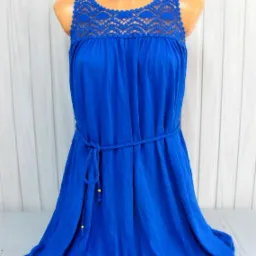 Kobaltowa sukienka damska bez rękawów z koronkowym dekoltem i sznurkowym paskiem, prezentowana na manekinie na tle białych paneli ściennych.