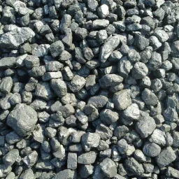 Błyszczące bryłki węgla kamiennego, różnej wielkości, tworzące zwartą, nieregularną teksturę. Naturalne światło podkreśla grafitową barwę i fakturę.