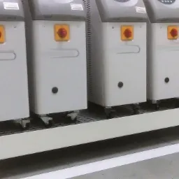 Platforma z metalową kratą pod zbiornikami, spawana konstrukcja nośna, biała linia na podłodze.