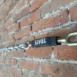 Wzmocnienie ściany z cegły za pomocą ściągu sprężającego marki Sivel, widoczne elementy mocujące i lina stalowa.