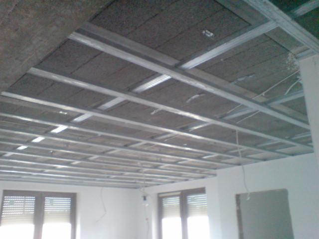 Montaż sufitu podwieszanego z izolacją akustyczną na metalowej konstrukcji. Widoczne profile i płyty izolacyjne, przygotowanie do dalszych prac wykończeniowych.